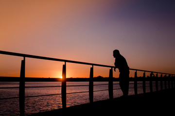Sunset over the river, man looks at horizon.