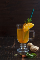 ginger tea with saffron in a glass Irish glass with a tube on a dark wooden background