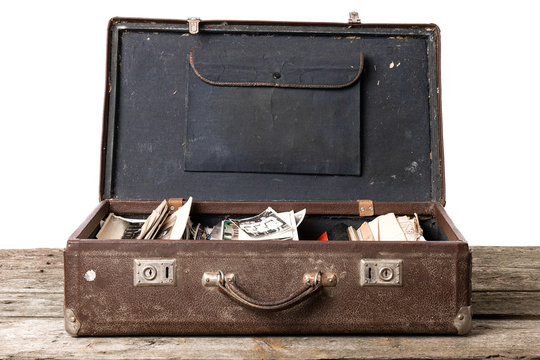 Open vintage brown suitcase with black and white photos stands on the wooden table