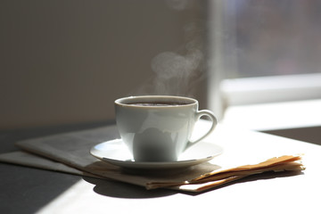 Delicious coffee and newspaper on sunlit table. Good morning