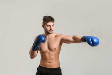 Sporty male boxer on grey background