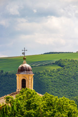 Church of Santa Caterina bell tower against blurred green idyllic springtime overcast landscape in...