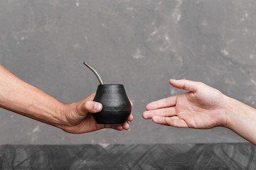 A man sharing Yerba Mate tea in gourd with sipped metal straw.