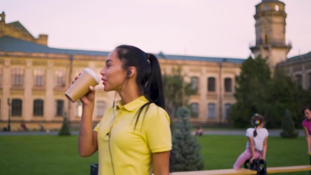 Young attractive latino girl walks in the park and drinks coffee 4K