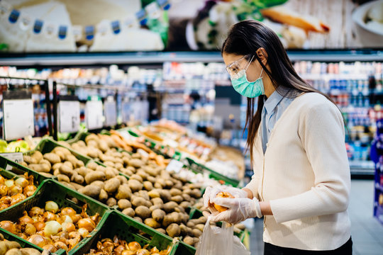 Woman with hygienic mask buying in supermarket grocery store for fresh greens,budget shopping for supplies during the pandemic.Buying organic vegetables sustainable produce.Plant based diet.Nutrition
