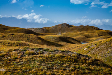Beautiful landscape. Scenic lake between mountains. Kyrgyz nature. Grass on hills.
