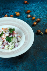 vegetable salad in a plate on a blue background with onions and green oystics near