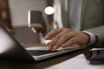 Man working with laptop in office, closeup of hand
