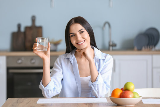 Beautiful Young Woman Drinking Water In Kitchen