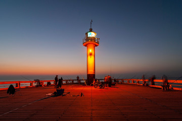 The lighthouse of Oostende (Ostend in English) at the end of the pier at night with a group of...