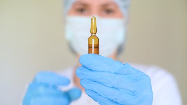 a young female doctor taps a glass medicine bottle with her finger. The concept of medicine