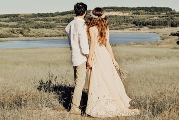 Beautiful couple having walking on the prairie. Young couple enjoying the sunset. Man and woman in love having romantic time. Family enjoying tender moment, happy marriage. Save the date.