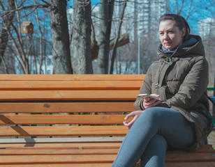 Obraz premium Beautiful young urban woman sitting on a bench with a phone