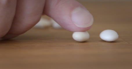 Finger adds a second bean to one already on wooden table top, metaphor for bean counting accountants. Macro with shallow focus