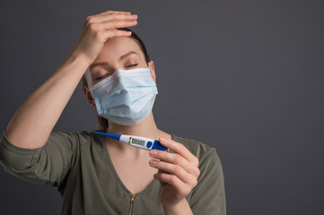 Girl with a high temperature mask in thermometer, symptoms of a virus or coronavirus. Against a...