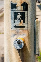 Pedestrian crosswalk sign worn off concrete poll with push button control.  closu-up, background, safety concept