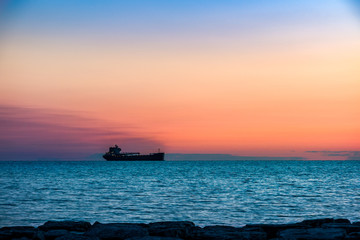 Fototapeta na wymiar Tanker ship coming into harbor, on a background of sunset sky