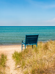 Summer, a sandy path-way to the beach through the long grass and over the sand dune to a solitary chair