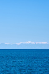 Fototapeta na wymiar Tropical blue sea and blue sky with mountains on a horizon as a natural background. Copy space.