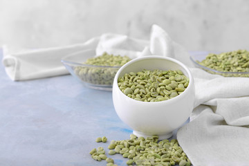 Bowl with green coffee beans on table