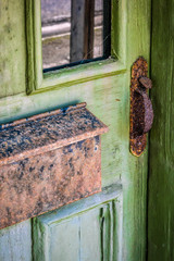 Green  wooden door with mottled rusted mailbox