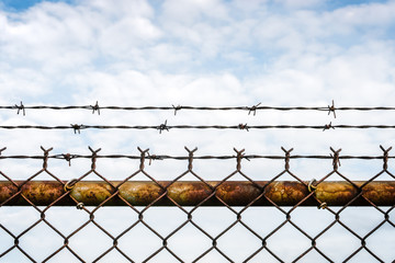 Vibrant colors, rusty chain link fence topped with barbed wire. Selective focus - background - graphic