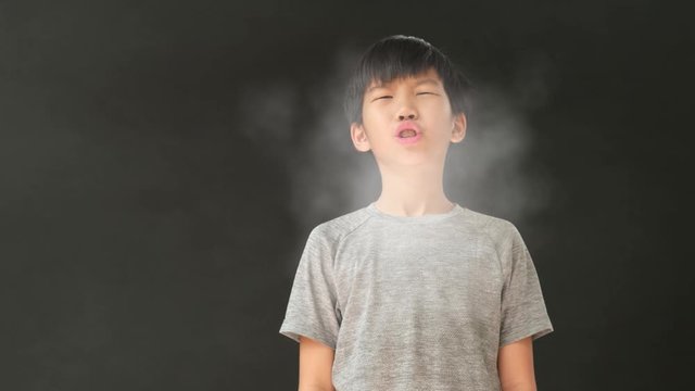4k young Asian boy in a smog enviroment has sneeze and spread white germ cloud from mount and nose on black background