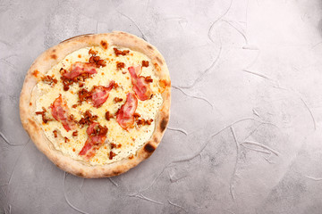 Delicious fresh Pizza with tomatoes, mashrooms, bacon and cheese mozzarella on the stone table. Top view