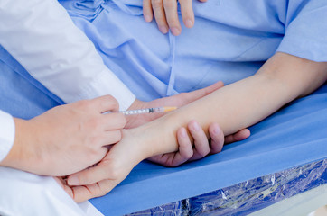 male doctor injecting an old woman in a hospital bed