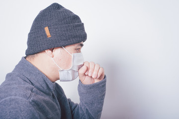 man turned sideways wearing a hat and wearing a mask. Discomfort and prevent the corona virus or covid-19 on white background,in house
