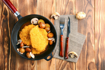 Chicken fillet in the grill pan. Grilled meat with cheese and mashrooms and wooden background