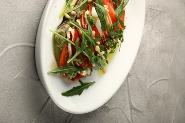 caprese salad with mozzarella arugula and pesto in white plate closeup
