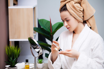 Pretty girl doing cosmetic procedures at home in front of mirror