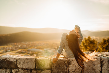 Optimistic young woman listening to music podcast stream over headphones,enjoying in nature at sunset.Day in nature.Stress menagement.Idea inspiration.Loving music,enjoying life.Energized young woman
