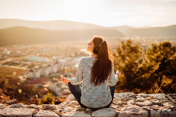 Optimistic young woman listening to music podcast stream over headphones,enjoying in nature at sunset.Musical therapy.Day in nature.Mindfulness guided meditation.Stress menagement.Idea inspiration.