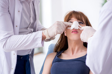 Two male doctors and young woman in plastic surgery concept