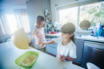 two young girls sisters cooking at home
