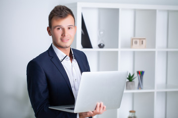 Handsome young worker working in a company office with documents and a laptop