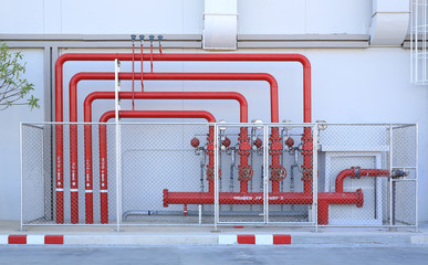 Red pipe of Fire Fighting systems in industrial zone in iron mesh fence. Water station in factory area zone.