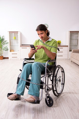 Young male invalid in wheel-chair suffering at home