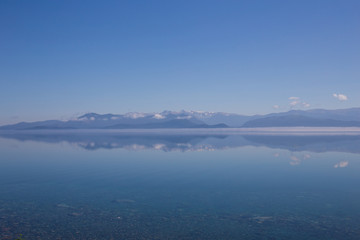panorama of blue calm lake and reflection of mountains, clouds in the water