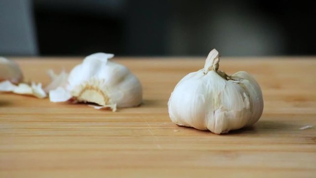 Chef's hand peels garlic on a cutting board