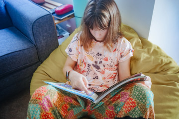 young teen girl reading at home, home schooling, remote education at quarantine