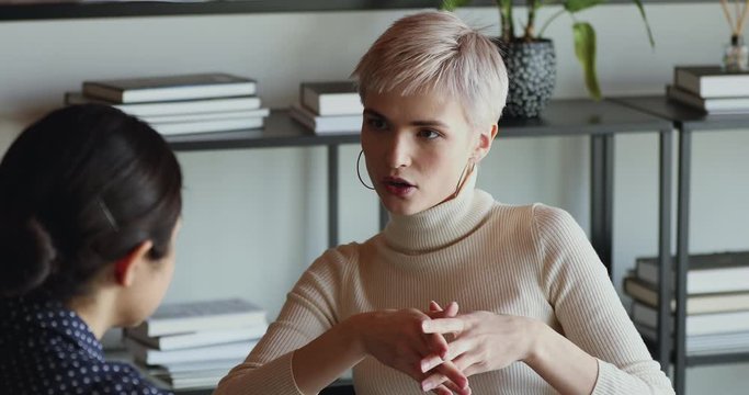Confident female insurer consulting client about insurance benefits. Young businesswoman mentor, saleswoman, customer service manager teaching helping intern, giving business advice at office meeting.