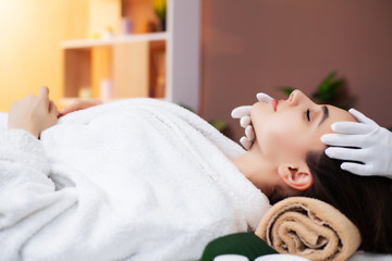 Pretty woman receiving facial massage in spa salon