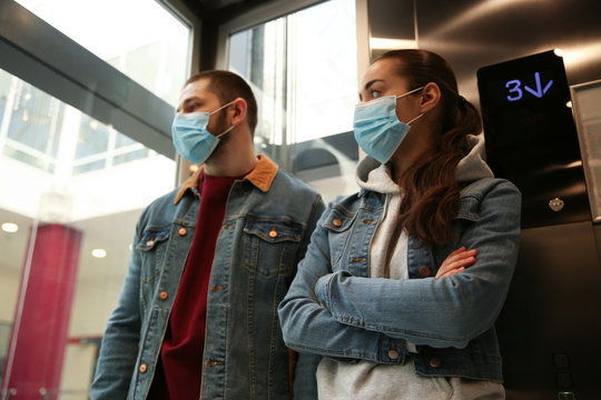 Couple wearing disposable masks in elevator. Dangerous virus