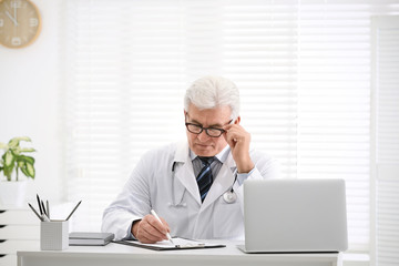 Senior doctor working at table in office