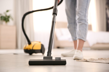 Young woman using vacuum cleaner at home, closeup - obrazy, fototapety, plakaty