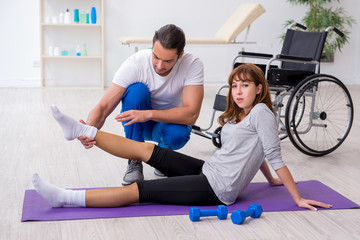 Fototapeta na wymiar Leg injured woman doing sport exercises with personal coach