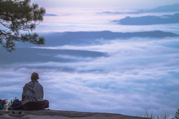 woman meditating on a rock at sunrise mountain morning